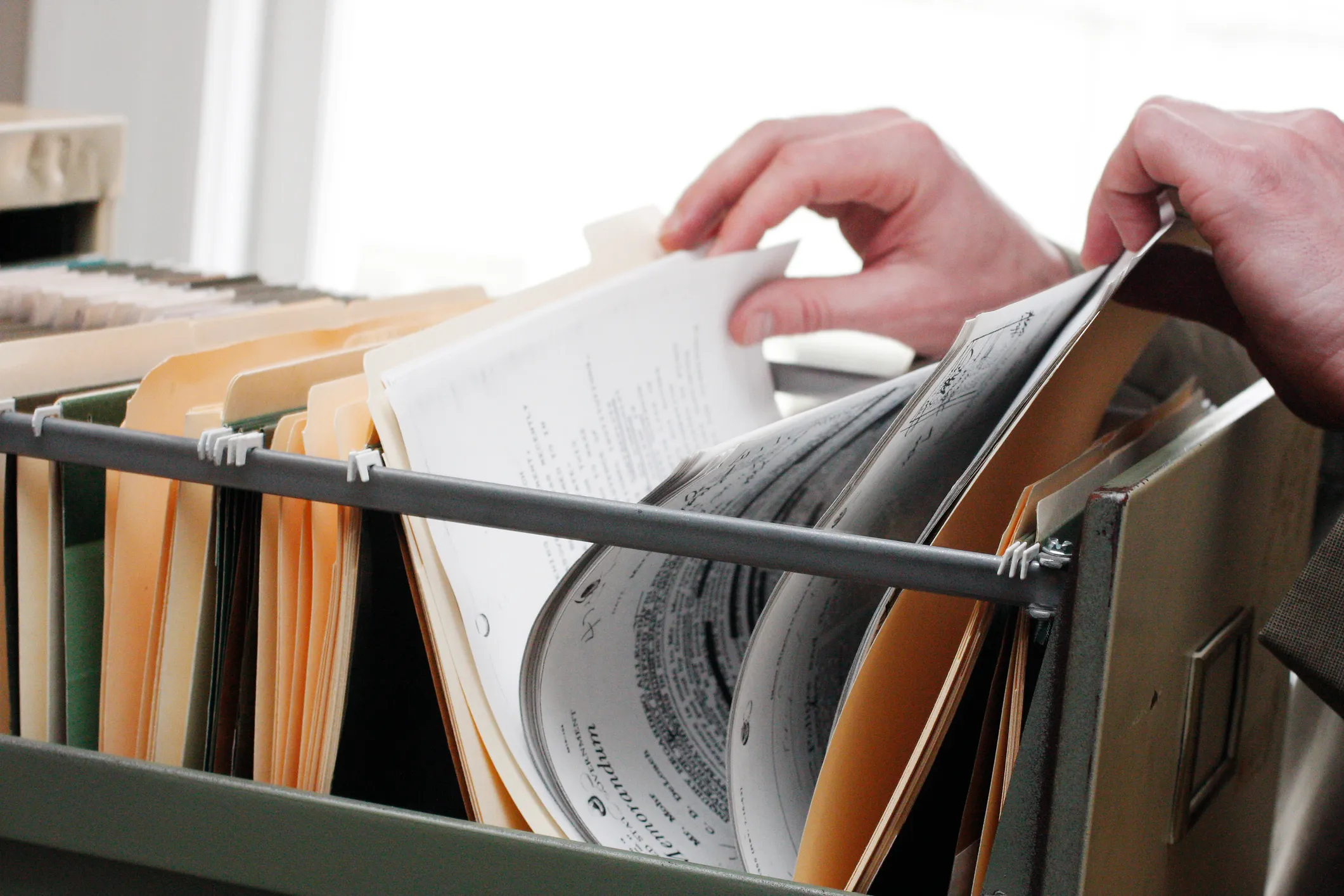 Someone going through paperwork in a cabinet.