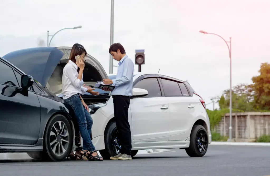 man and woman getting insurance info after a car wreck.