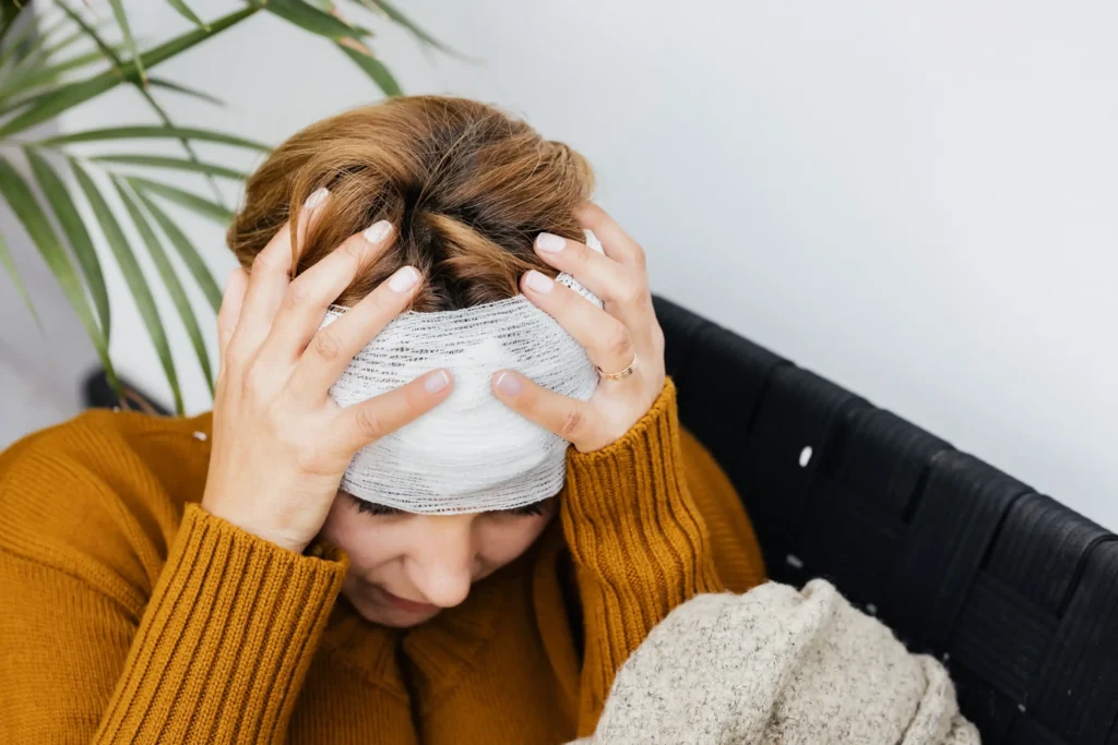 A woman with her head wrapped and holding it.