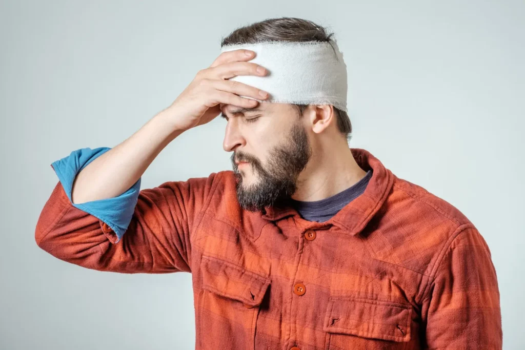A man holding his wrapped head.
