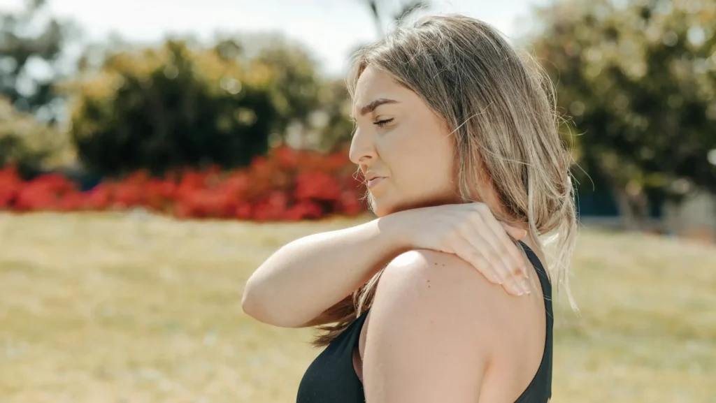 A woman holding her injured shoulder.