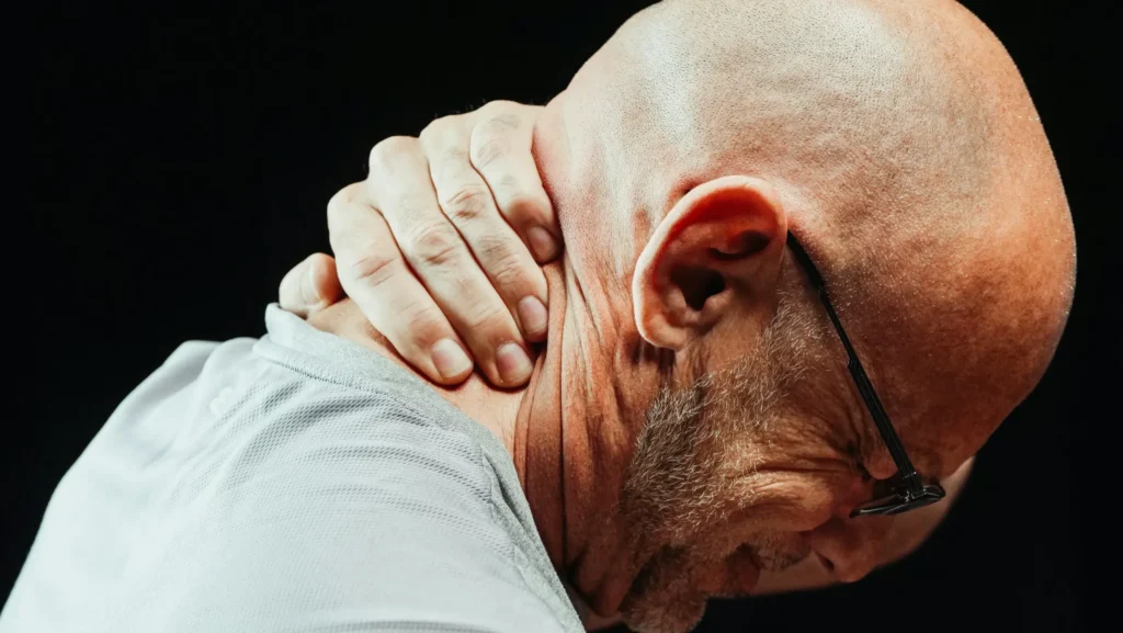 A man holding his neck in pain.